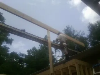 Carpenter setting a ridge beam over a new addition frame — Ice Dam Removal by Roofing Brothers in Carmichael
