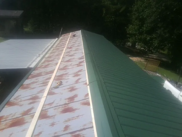 Old rusted panels beside newly installed green metal roofing — Wind Damage Roof Repair by Roofing Brothers in Carmichael
