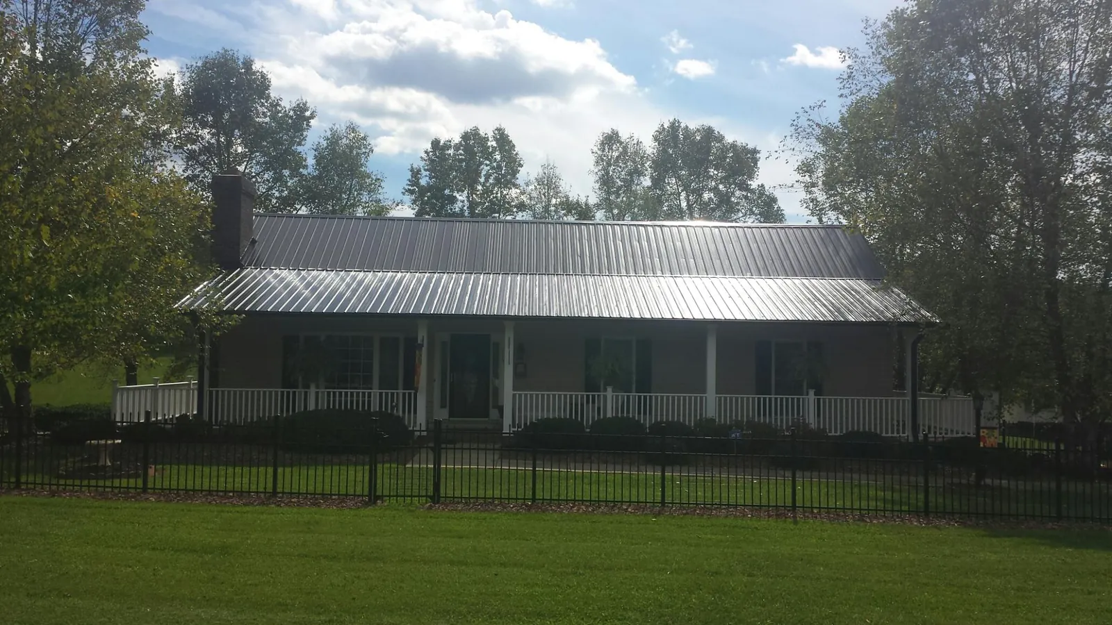 Gray metal roof on a brick ranch with a full width front porch — Gutter Guard Installation work by our crew in Carmichael
