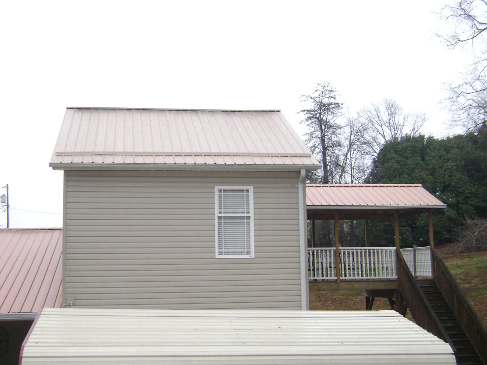 Tan metal roofs on a two story addition and attached porch, from a Roof Replacement job in Carmichael