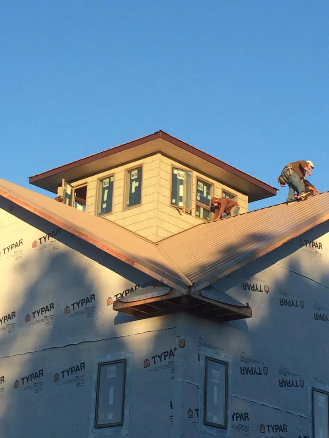 Roofers working around a rooftop cupola on a new metal roof at sunset — Roof Waterproofing in Carmichael by Roofing Brothers